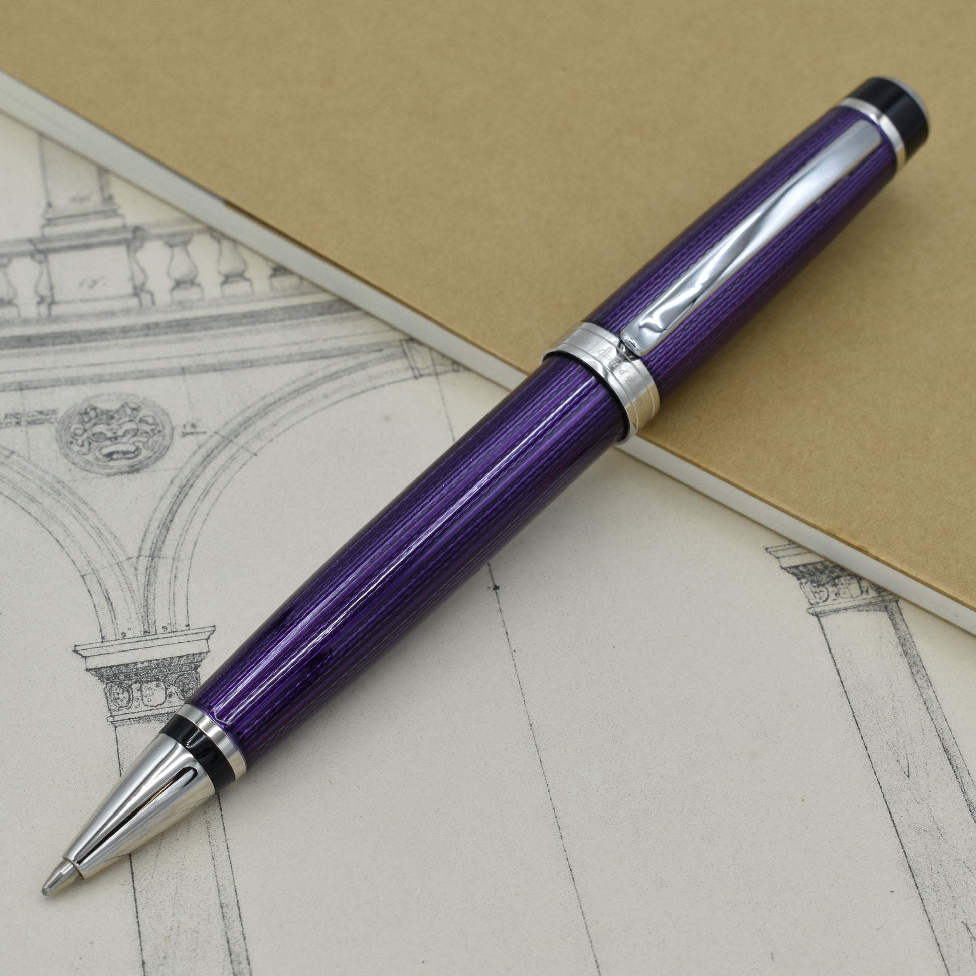 Incognito Purple B Ballpoint pen with antique architectural sketches and a notebook