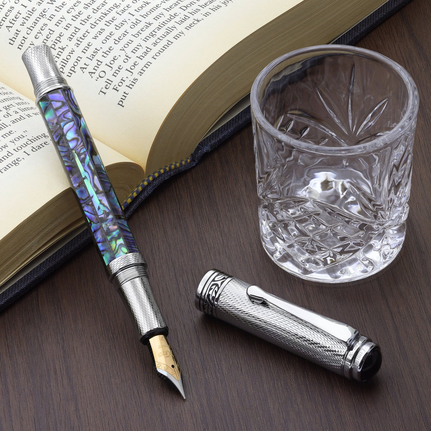 Maestro Paua Abalone Chrome F Fountain pen with a book and glass cup