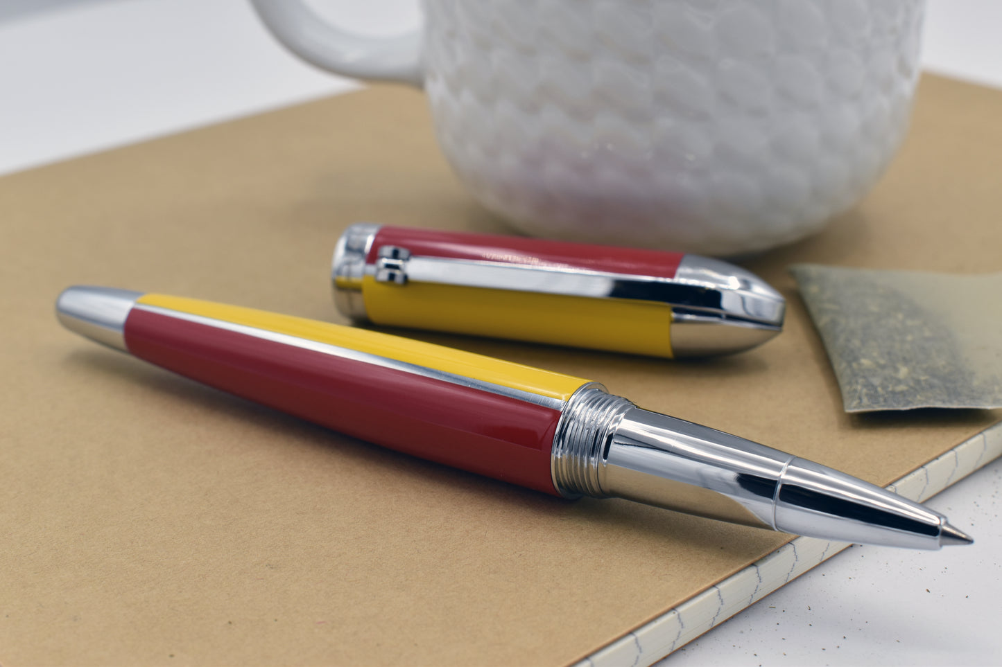 Visionary Aspen/Red R Rollerball pen next to a mug