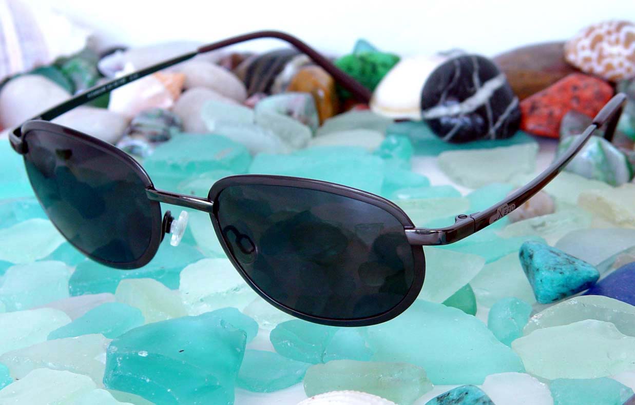 Xezo - Angled view of the front of a pair of Aeromaster 3100 sunglasses with colorful stones in the background