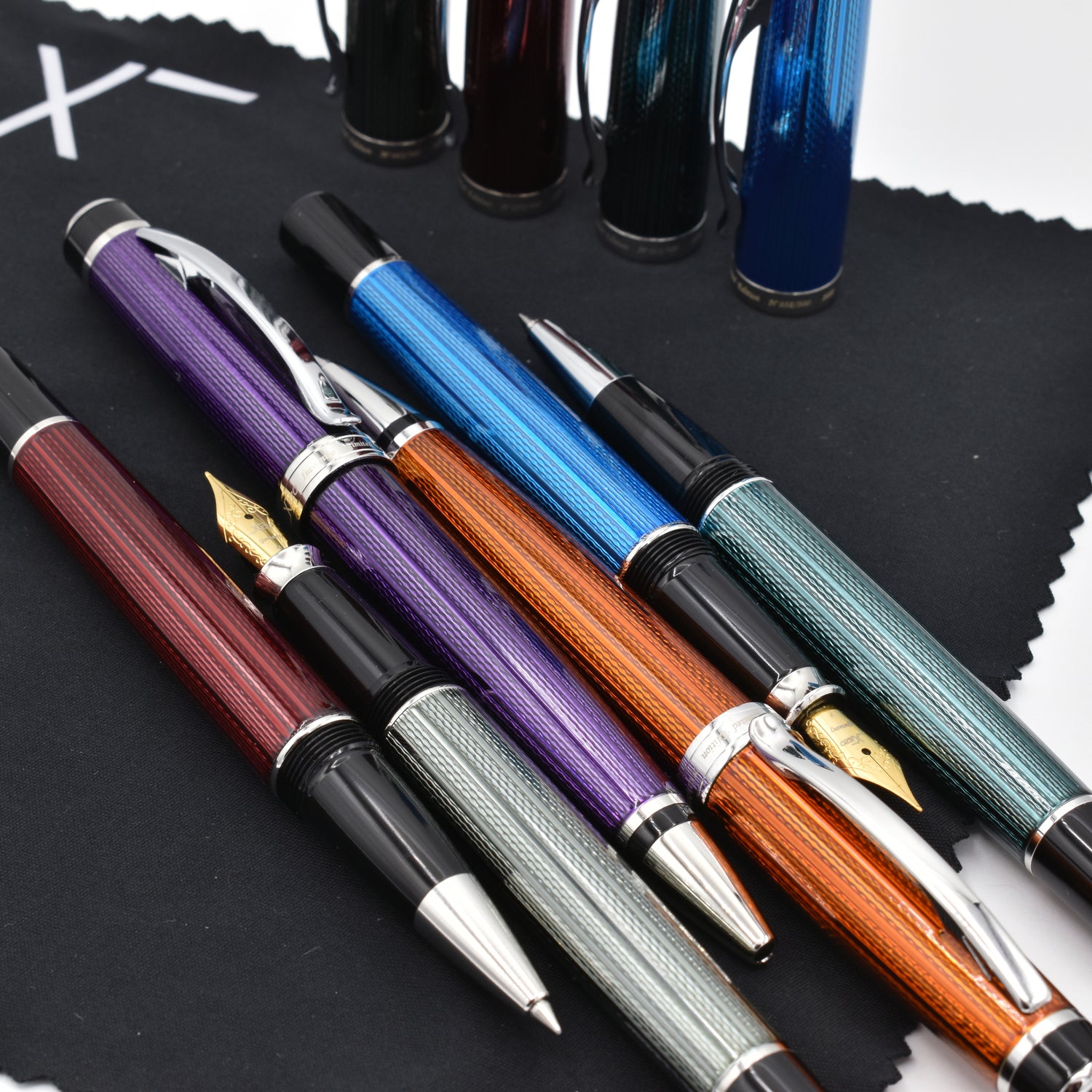A collection of Xezo Incognito pens laid next to each other on a black cleaning cloth