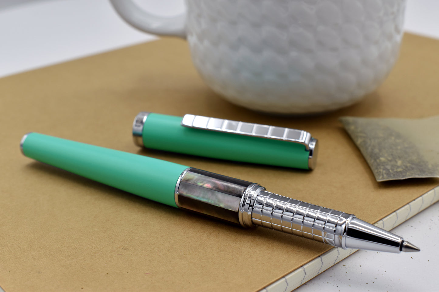 Speed Master Aqua Green R-BC Rollerball pen next to a mug
