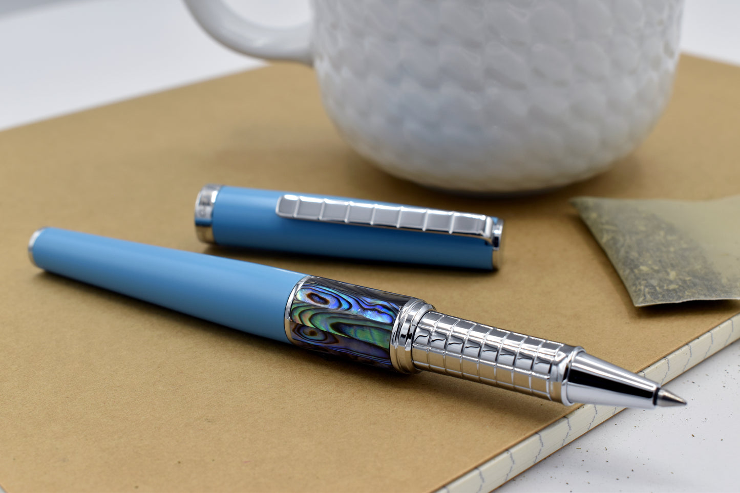 Speed Master Sky Blue R-AC Rollerball pen next to a mug