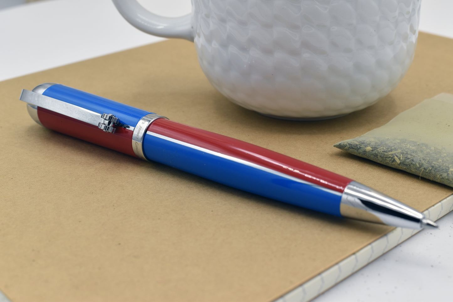 Visionary Red/Blue B Ballpoint pen next to a mug