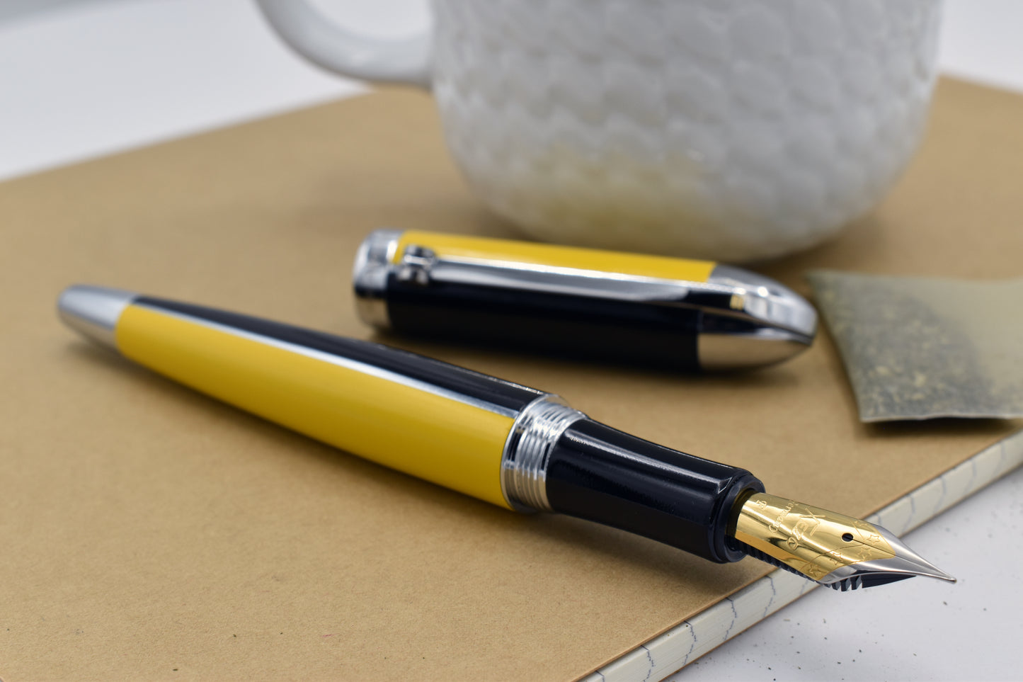 Visionary Speed Yellow/Black F Fountain pen next to a mug