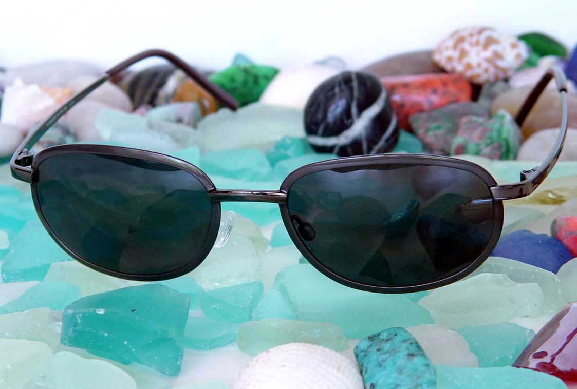 Xezo - Angled view of the front of a pair of Aeromaster 3100 sunglasses with colorful stones in the background